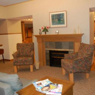 A cozy living room with a fireplace, two chairs, and a coffee table.