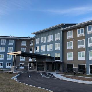 A modern multi-story hotel with a welcoming entrance and ample parking space.