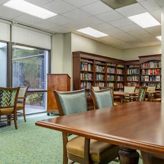 A quiet library space with bookshelves, a large table, and chairs for reading and study.