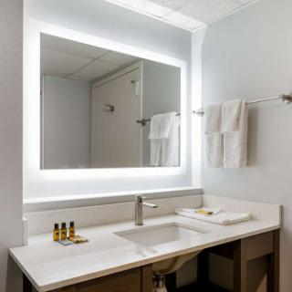 A modern bathroom featuring a well-lit vanity area with a sleek mirror and neatly arranged towels.