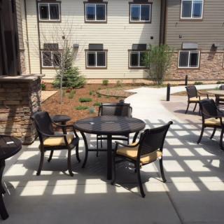 A sunny outdoor patio area with tables and chairs set up near a building.