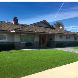 A suburban house with a well-maintained lawn under a clear blue sky.