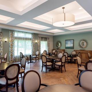 A well-lit dining room with elegant furniture and large windows.