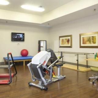 A spacious rehabilitation and fitness room equipped with various exercise machines and therapy tools.