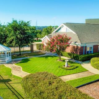 A quaint building surrounded by a well-manicured lawn and garden, featuring a charming gazebo.