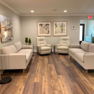 A modern waiting room featuring contemporary furniture, artwork, and warm wood flooring.