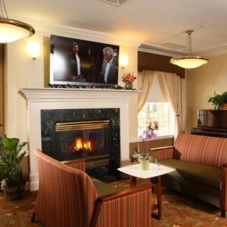 A cozy living room with a fireplace, sofas, and a television above the mantel.