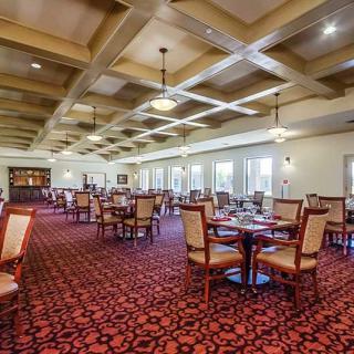 An elegant dining room with tables and chairs, featuring ceiling lights and large windows.