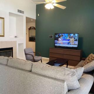 A cozy living room with a sofa facing a television on a green accent wall.