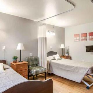 A cozy bedroom with twin beds and soft lighting, featuring a stylish armchair and decorative wall art.