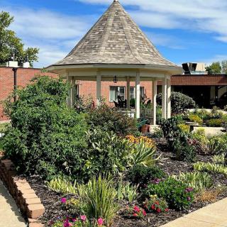 A beautiful garden with a central gazebo surrounded by lush plants and flowers.