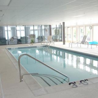 An indoor swimming pool with lounge chairs and large windows.
