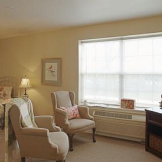 A cozy living room with comfortable chairs, a lamp, and a large window.
