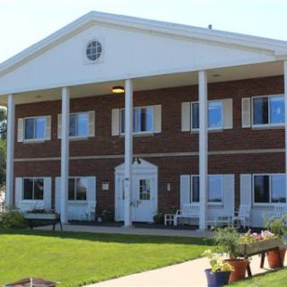 A two-story brick building with columns and a well-maintained lawn.