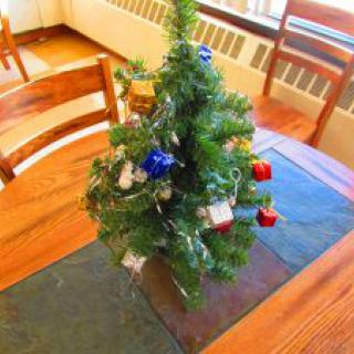 A small, decorated Christmas tree on a table, adorned with colorful ornaments.