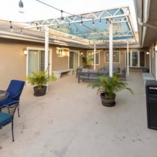 A modern outdoor patio with seating and potted plants under a partially covered area.