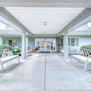 Covered entrance with benches leading to a residential building.