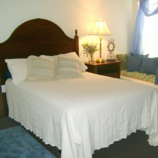 A cozy bedroom with a neatly made bed, pillows, and a lamp on the nightstand.