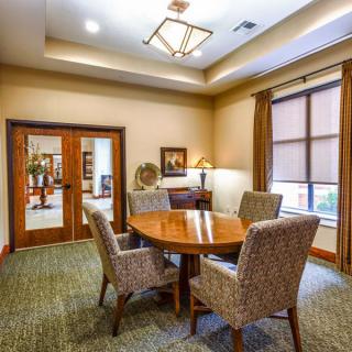 A well-lit meeting room with a round table and four upholstered chairs.