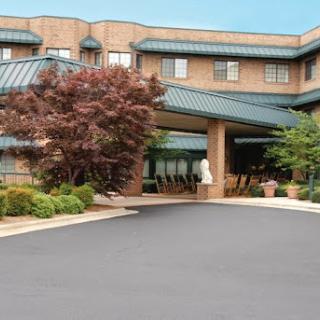 A welcoming entrance to a hotel featuring landscaped greenery and a modern architectural design.
