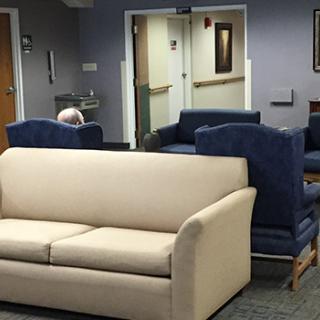 A waiting room with a beige sofa and blue chairs.