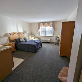 A cozy bedroom with a bed, nightstands, and an armchair near the window.