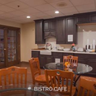 A cozy bistro cafe with wooden furniture and a small kitchen area.