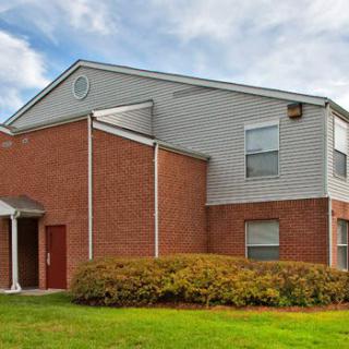 A suburban residential building with brick and siding exterior under a cloudy sky.