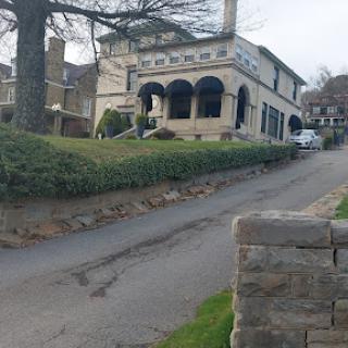 A picturesque view of a uniquely designed house nestled along a winding road.
