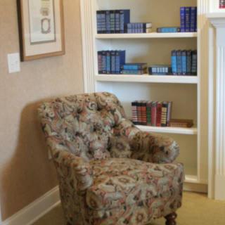 A cozy reading nook with a floral armchair and a bookshelf filled with books.