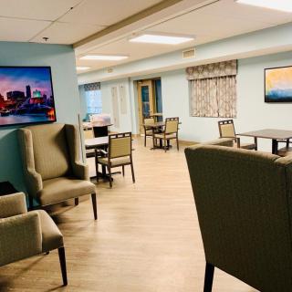 A cozy lounge area with chairs and tables, decorated with artwork on the walls.