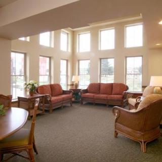 A spacious living room with ample natural light, featuring multiple sofas and large windows.