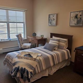 A cozy bedroom with a single bed, desk, and chair by the window.