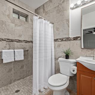 A modern bathroom featuring a shower, toilet, and sink with elegant tile work.