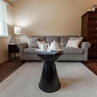A cozy living room featuring a comfortable gray sofa, a modern black coffee table with a teapot set, and a warm atmosphere.