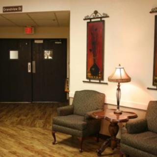 A cozy lobby area with chairs, a table, and a lamp next to double doors.