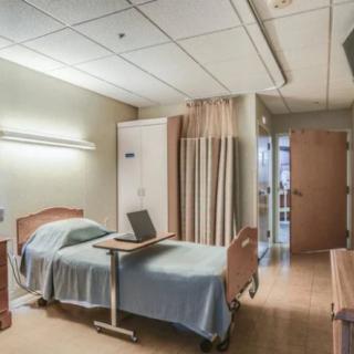 A clean and empty hospital room with a bed and medical equipment.