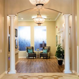 A welcoming entrance hall featuring elegant columns, cozy seating, and stylish lighting.