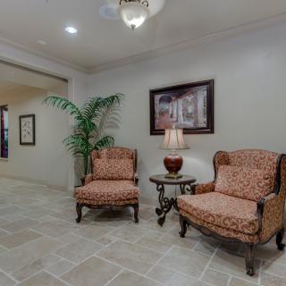 A cozy lobby area with two upholstered chairs and a side table topped with a lamp, complemented by a decorative plant and artwork on the wall.