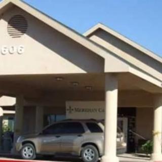 A car parked at the entrance of a beige building under clear blue skies.