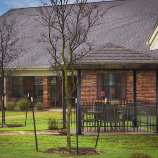 A brick house with a porch and neatly maintained lawn.