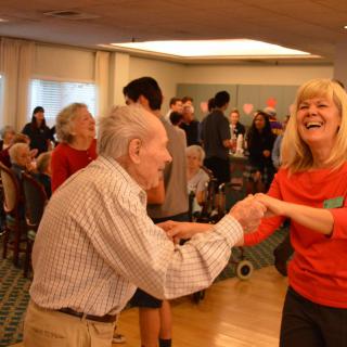 A joyful moment as seniors dance together at a community event.