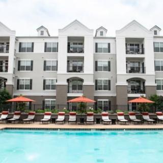 An apartment complex with a pool and lounging area.