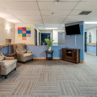 A modern waiting room with comfortable seating, a television mounted on the wall, and vibrant artwork displayed above a side table.