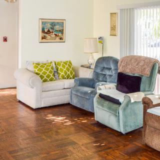 A cozy living room with a sofa, two armchairs, and decorative cushions on a wooden floor.