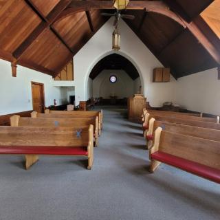 Interior view of a church with wooden pews and an arched ceiling.