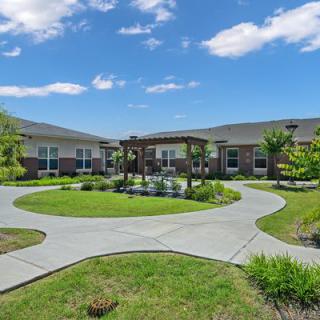 A well-maintained courtyard with a circular pathway surrounded by green landscaping under a blue sky.