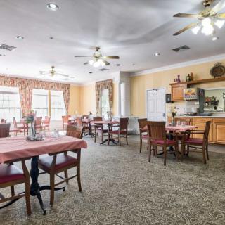 A cozy dining area with several tables and chairs, adorned with soft lighting and ceiling fans.