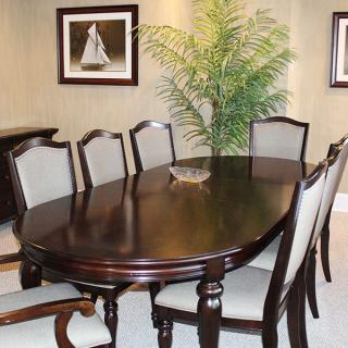 A dining room with a dark wooden table and six chairs, complemented by wall art and a decorative plant.
