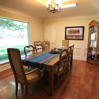 A cozy dining room with a wooden table, elegant chairs, and a large window providing natural light.